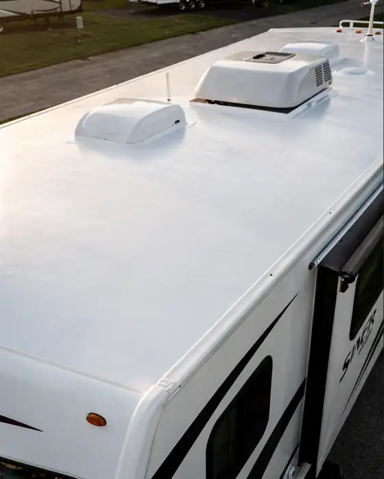 Renewed white RV roof after repair with roof-mounted air conditioner